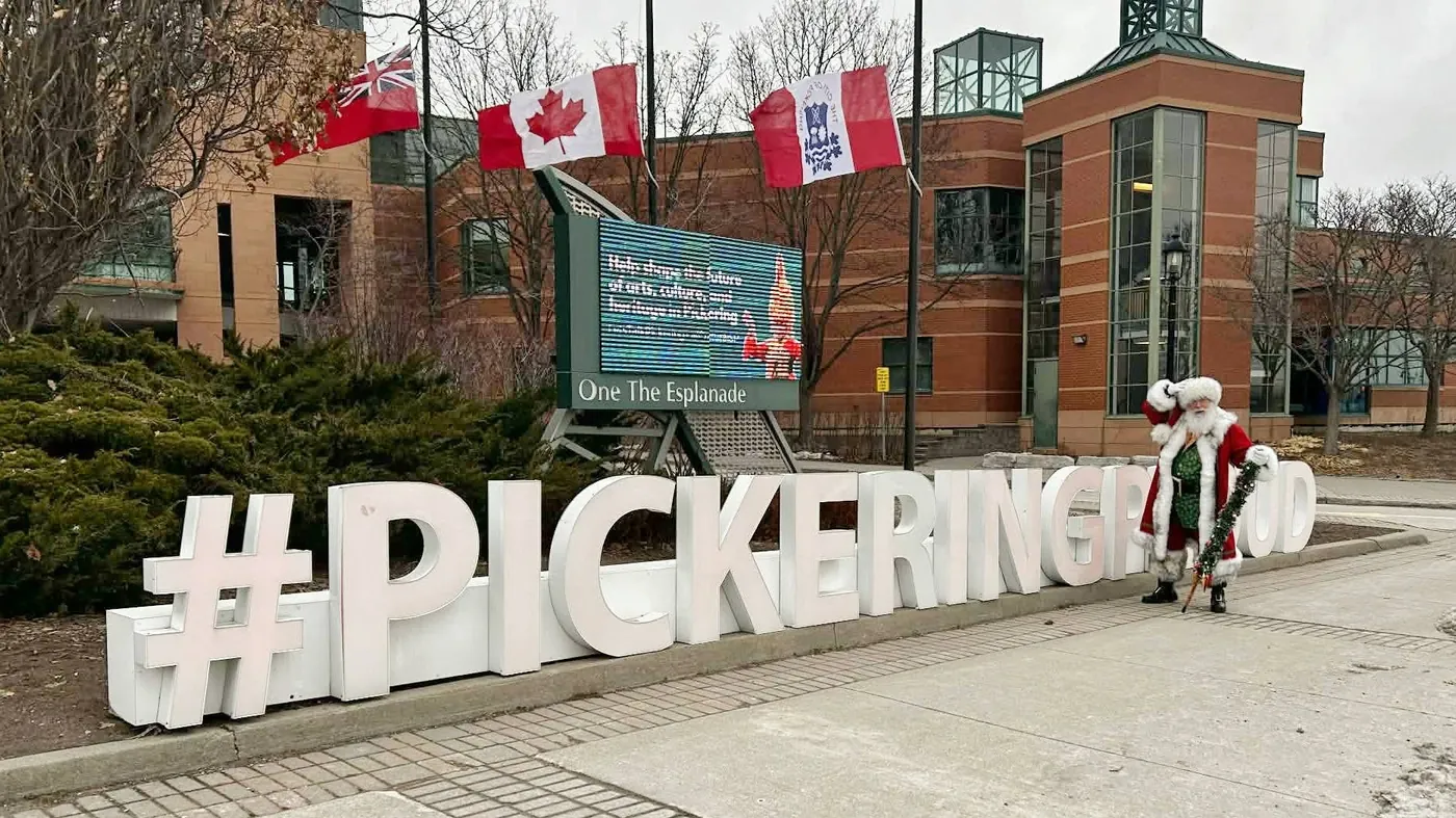 Santa Stu standing beside the Pickering sign outside a civic building